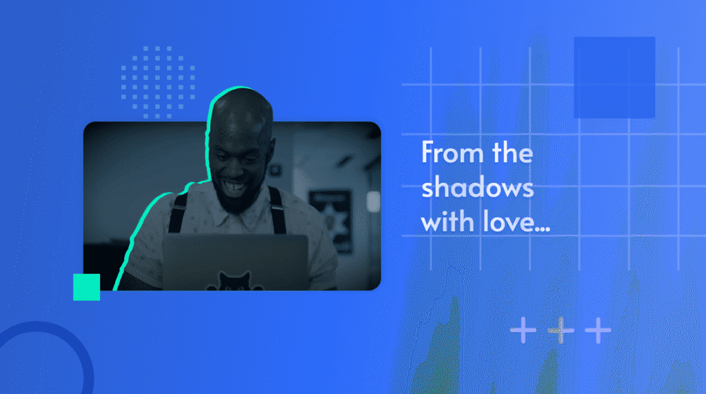 Photo of a smiling man at a laptop in low light, captioned 'From the shadows with love'
